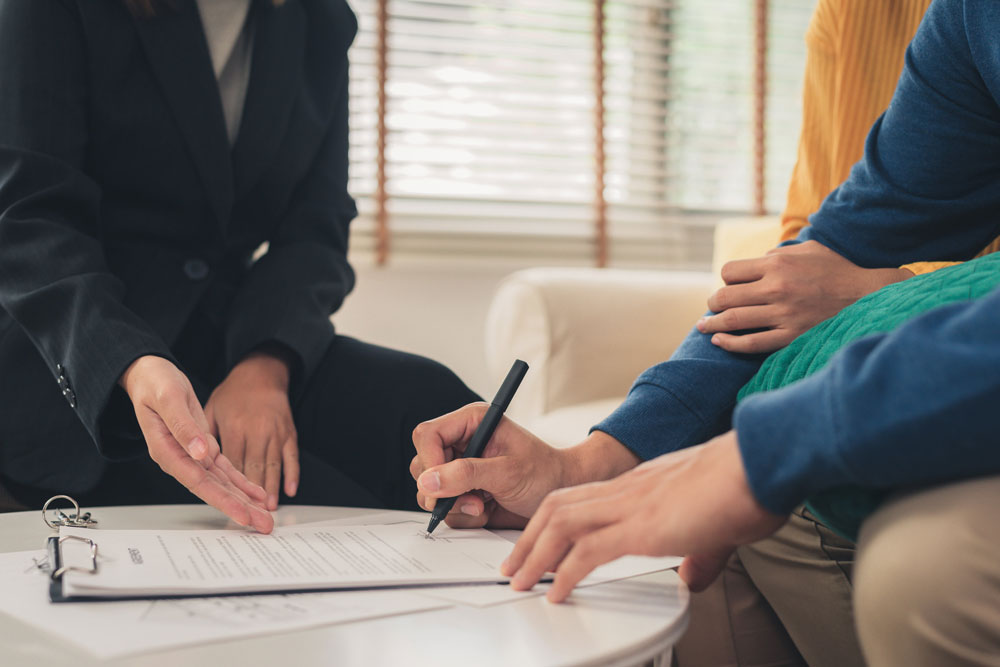 Un ejecutivo asesorando a varias personas en la firma de un contrato