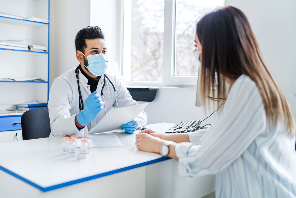 Un doctor con mascarilla explicando a su paciente los términos de su servicio